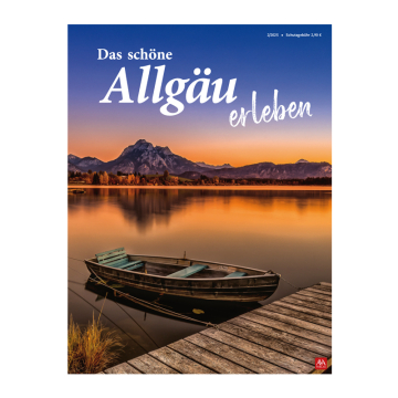 Ein See mit Bergen im Hintergrund, vorne ein Steg und ein Holzboot, Dämmerung